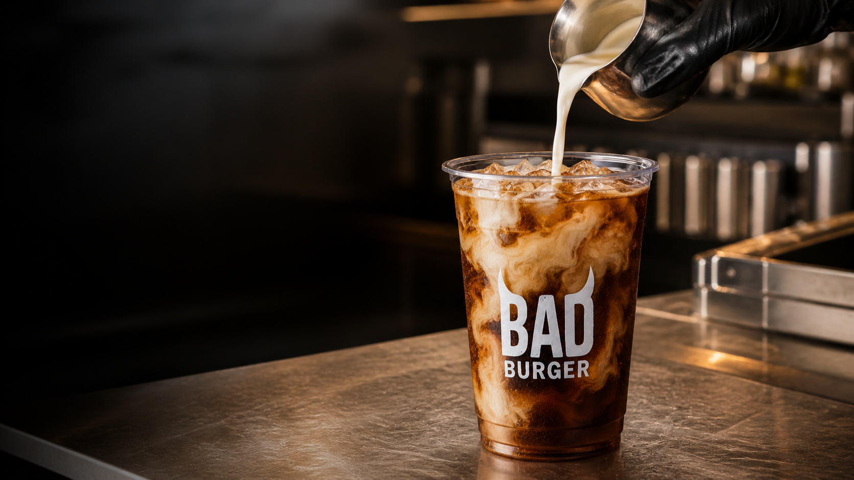 A 20 oz. dirty soda hero shot, cream and syrup tumbling into the cup in moody close-up